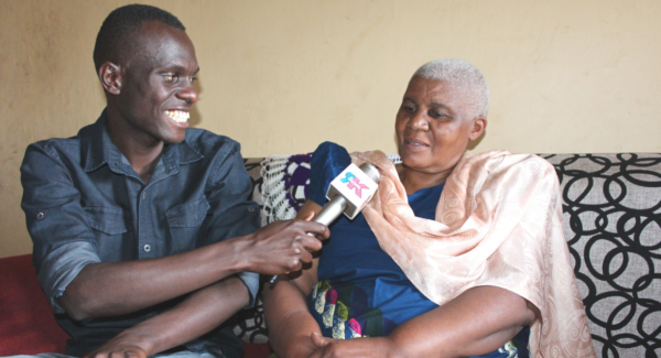 Radio host interviews woman. he is smiling and holding a mic close to her mouth.