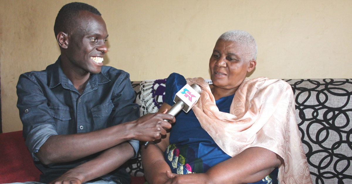 Radio host interviews woman. he is smiling and holding a mic close to her mouth.