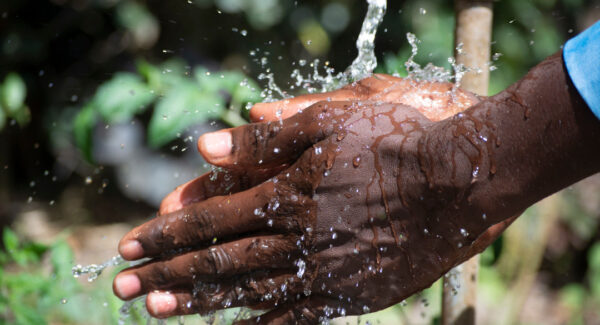 pair of hands cups water from a borehole