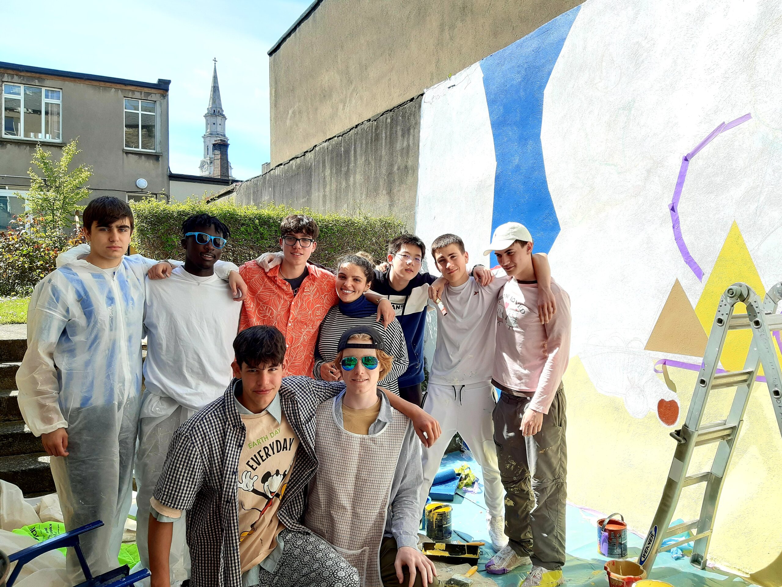 fine artist poses with Clongowes art students with the painted mural behind group