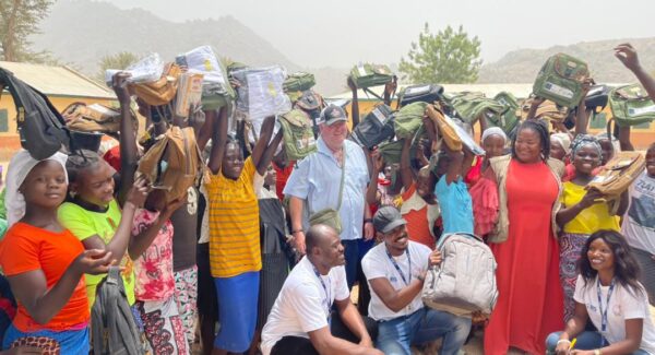 Tim in group photo with children receiving school supplies