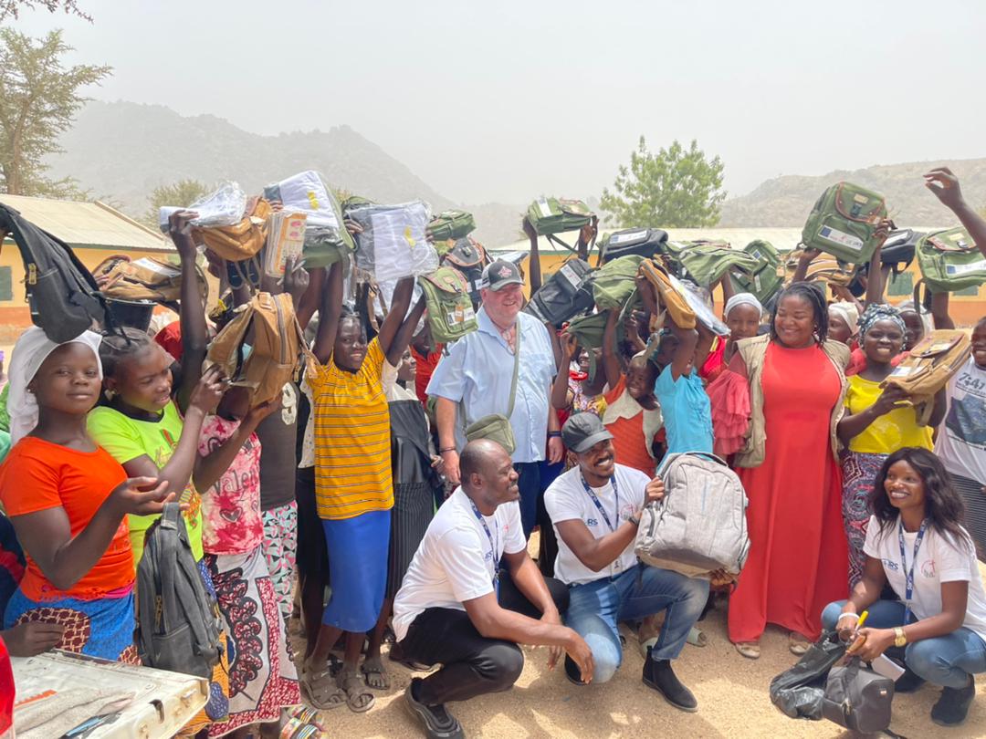 Tim in group photo with children receiving school supplies