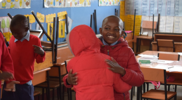 Children from Upendo programme hug in the classroom