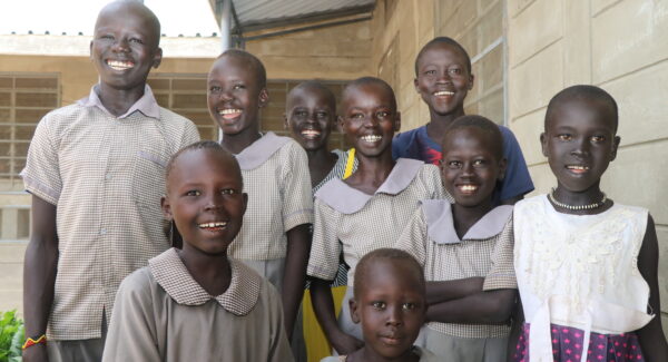 school girls pose and smile for a group photo in their school uniforms