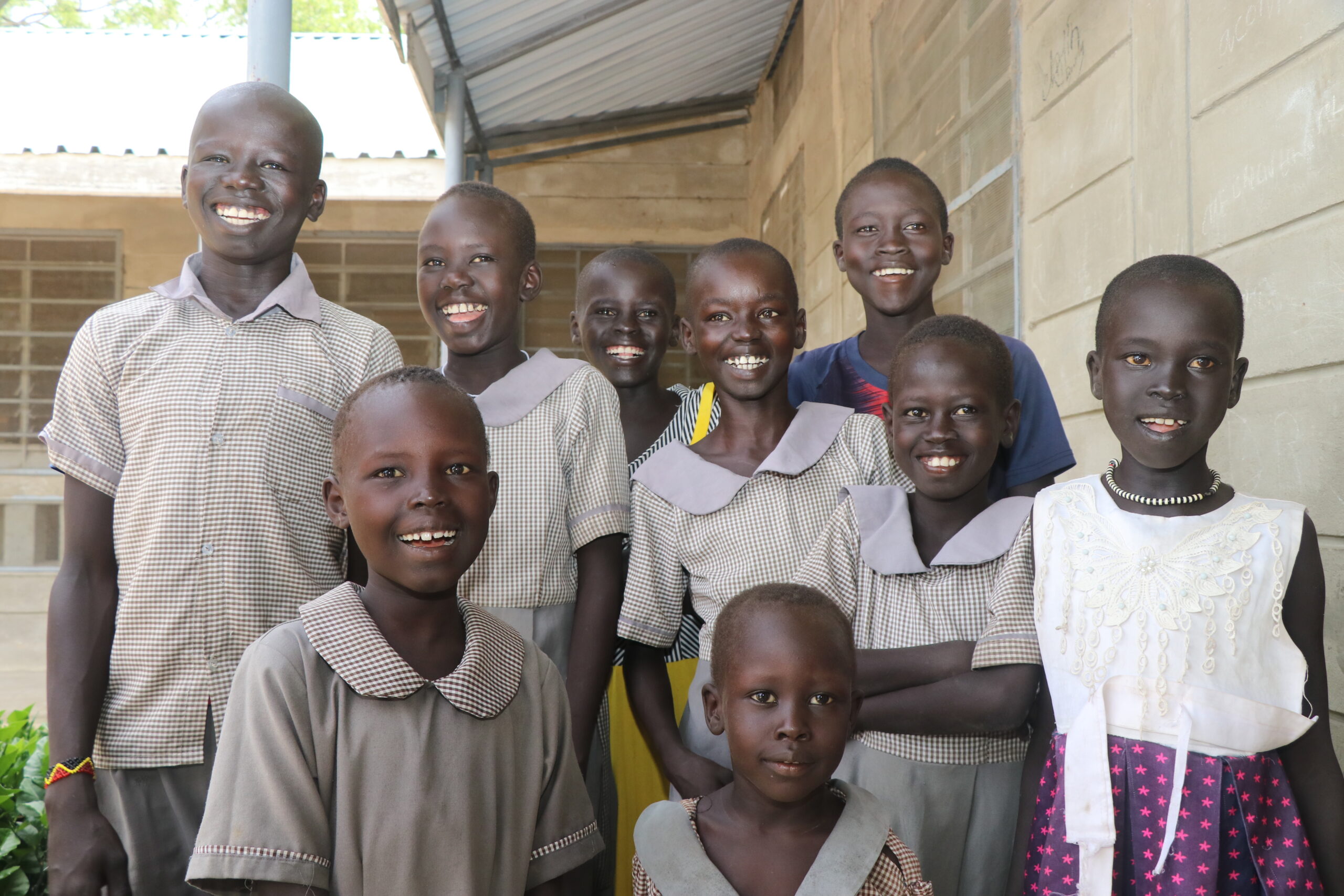 school girls pose and smile for a group photo in their school uniforms