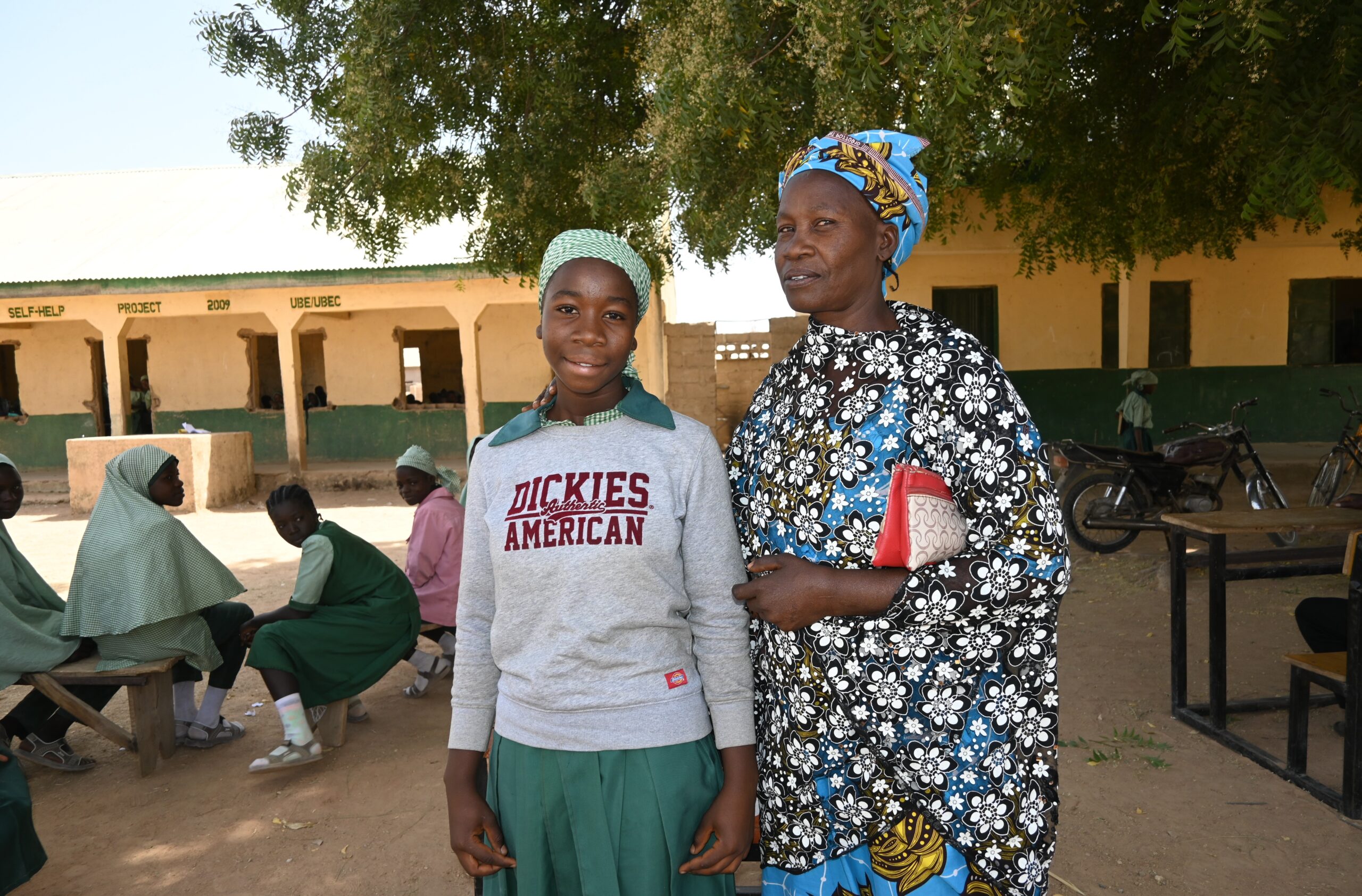 Sarah, a teacher poses for photo outside with student