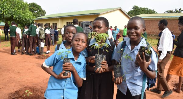 Students pose for photo with tree saplings for planting. they are happy and smiling.
