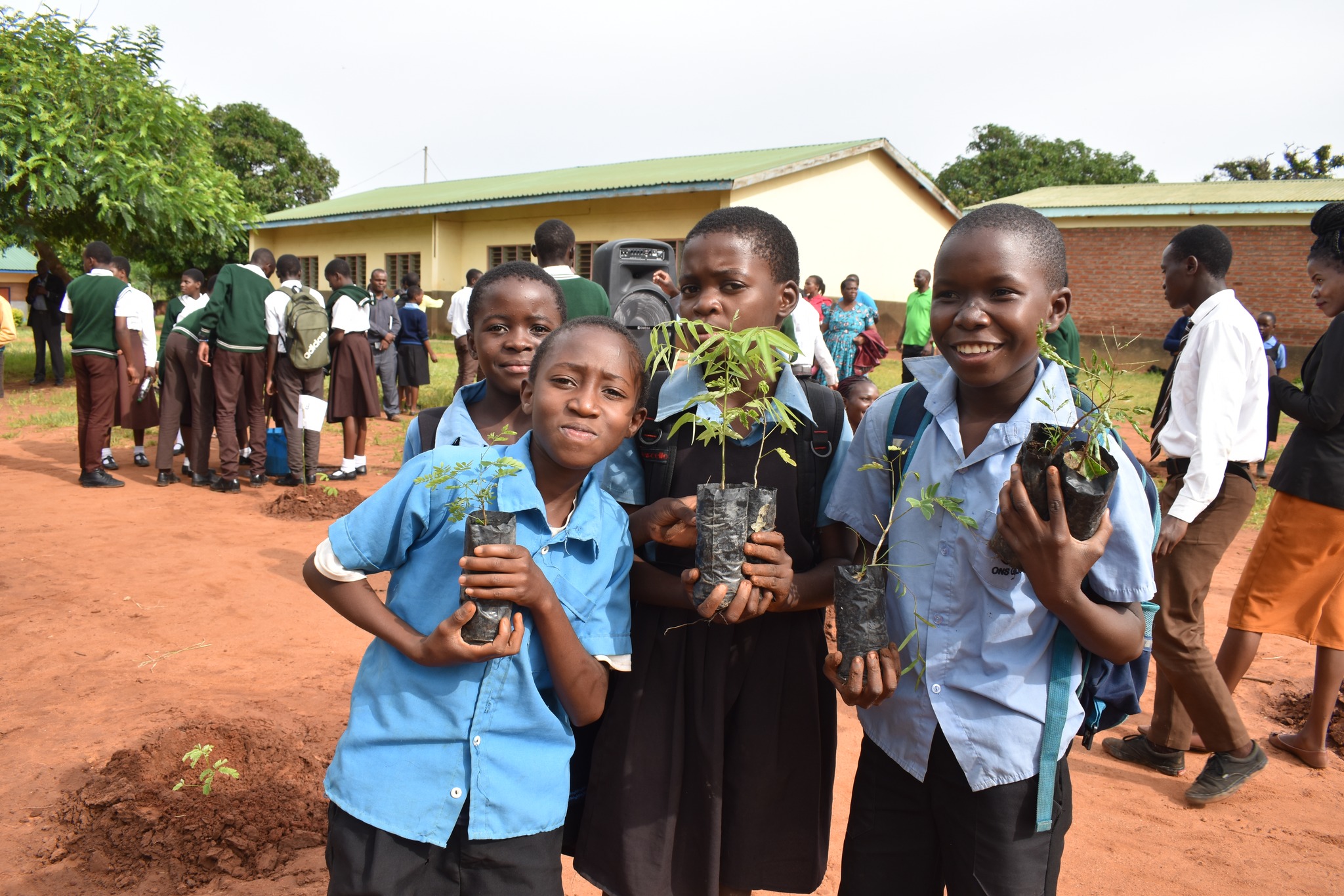 Students pose for photo with tree saplings for planting. they are happy and smiling.