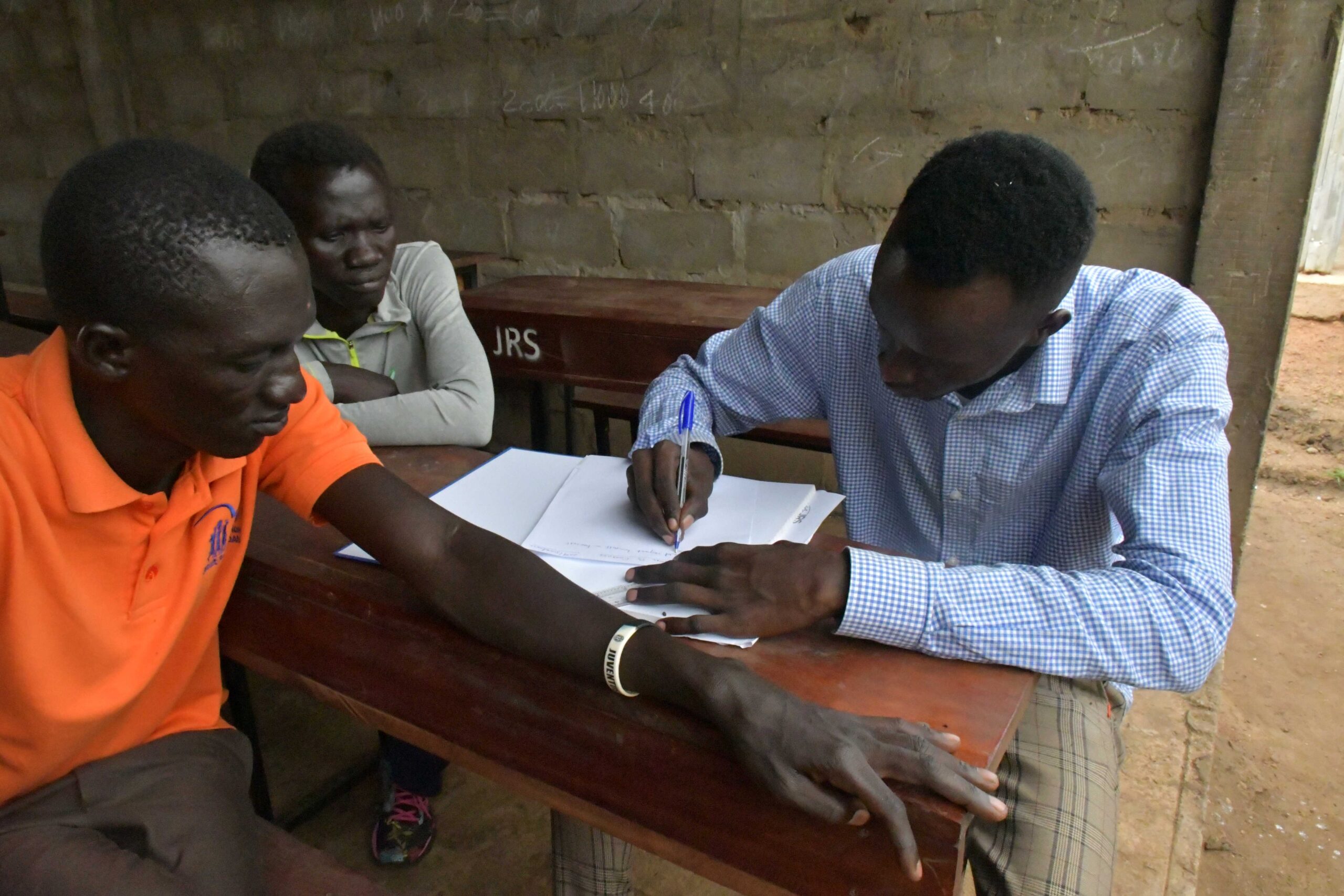 Teachers training. Two men sit at a school desk looking over a paper or textbook