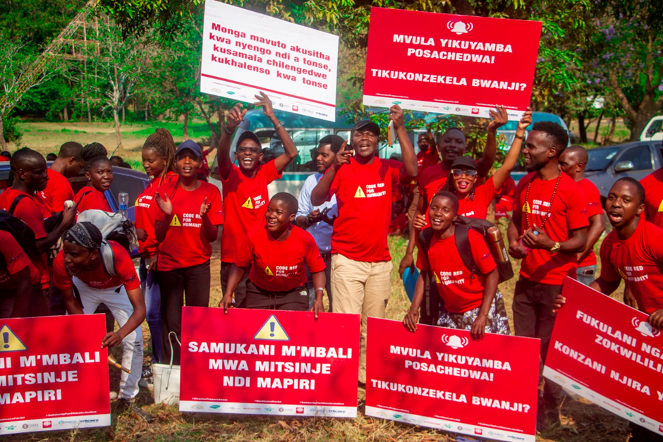 Climate activists at Code Red for Humanity rally post in red t-shirts and red posters calling for environmental policy