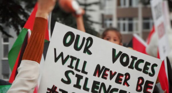 photo of Palestine solidarity march. a sign reads: 'our voices will never be silenced'