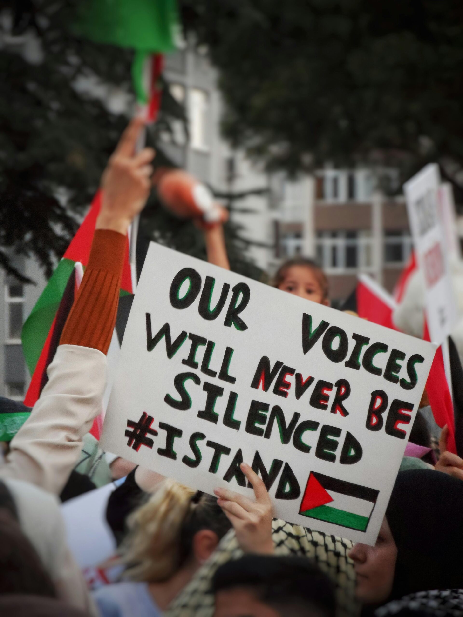 photo of Palestine solidarity march. a sign reads: 'our voices will never be silenced'