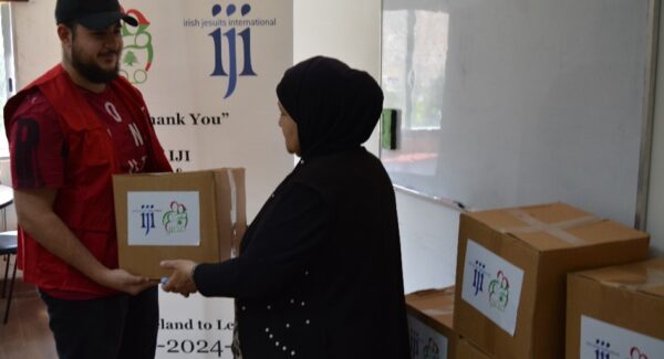 women receives food aid. the box has IJI and MASIR logos on it.