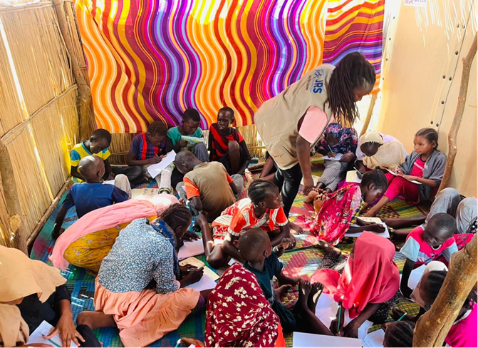 children sit on the floor with paper and pens learning