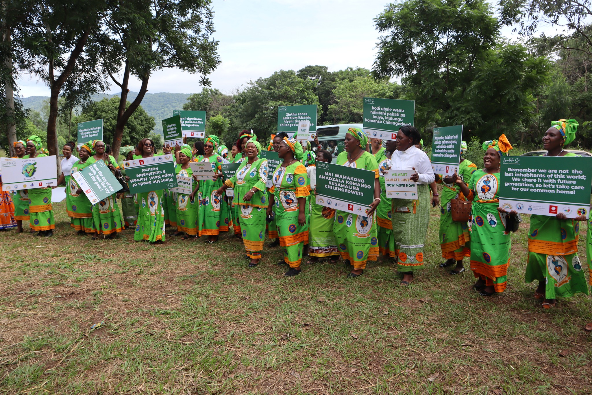women in Malawi hold placards calling for climate action & protection of the environment.