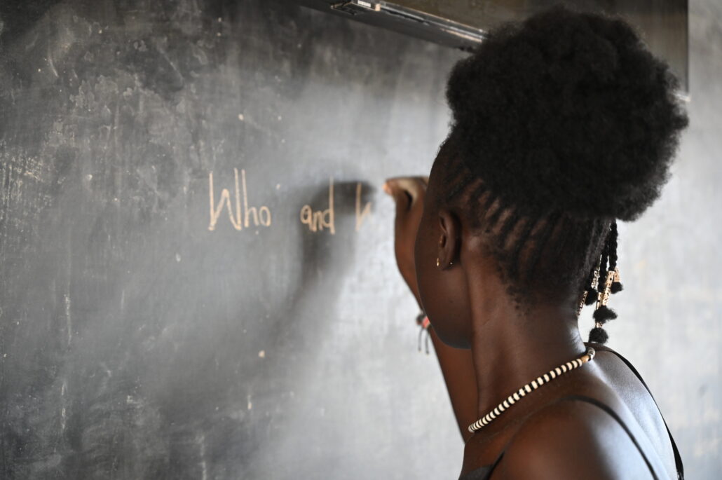 Athiei Dut Malual, a student teacher at SPCECC in Rumbek South Sudan writes on a blackboard with chalk