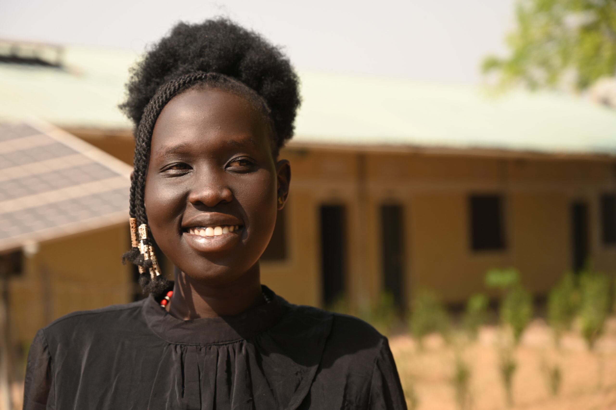 Athiei Dut Malual smiles standing outside her classroom in Rumbek, South Sudan.