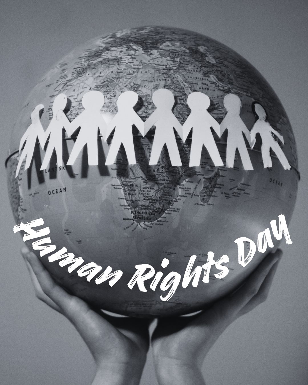 Someone is holding up a globe of the world. paper cut outs of people hold hands around the globe.