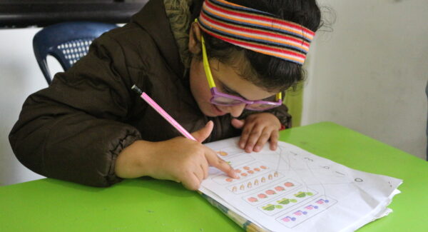 Nadia wears thick glasses and is reading her textbook