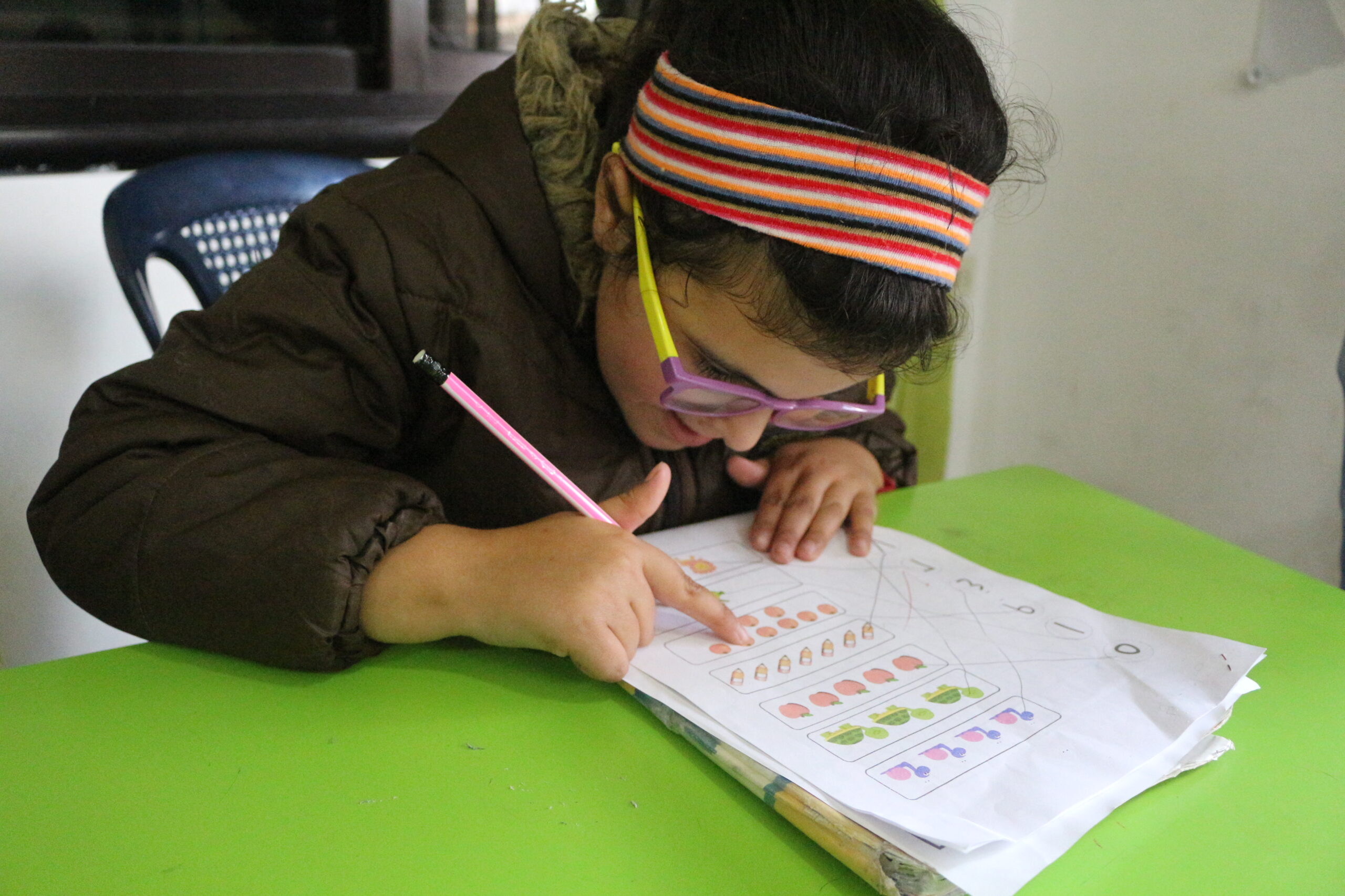 Nadia wears thick glasses and is reading her textbook