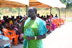 Mary Ayen Mading, the Women Representative, speaks to crowd with microphone 