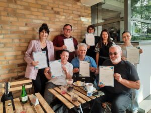 refugees pose with certificates after completing language course.