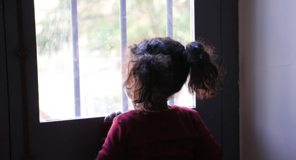 a girl looks out from a window in Lebanon.