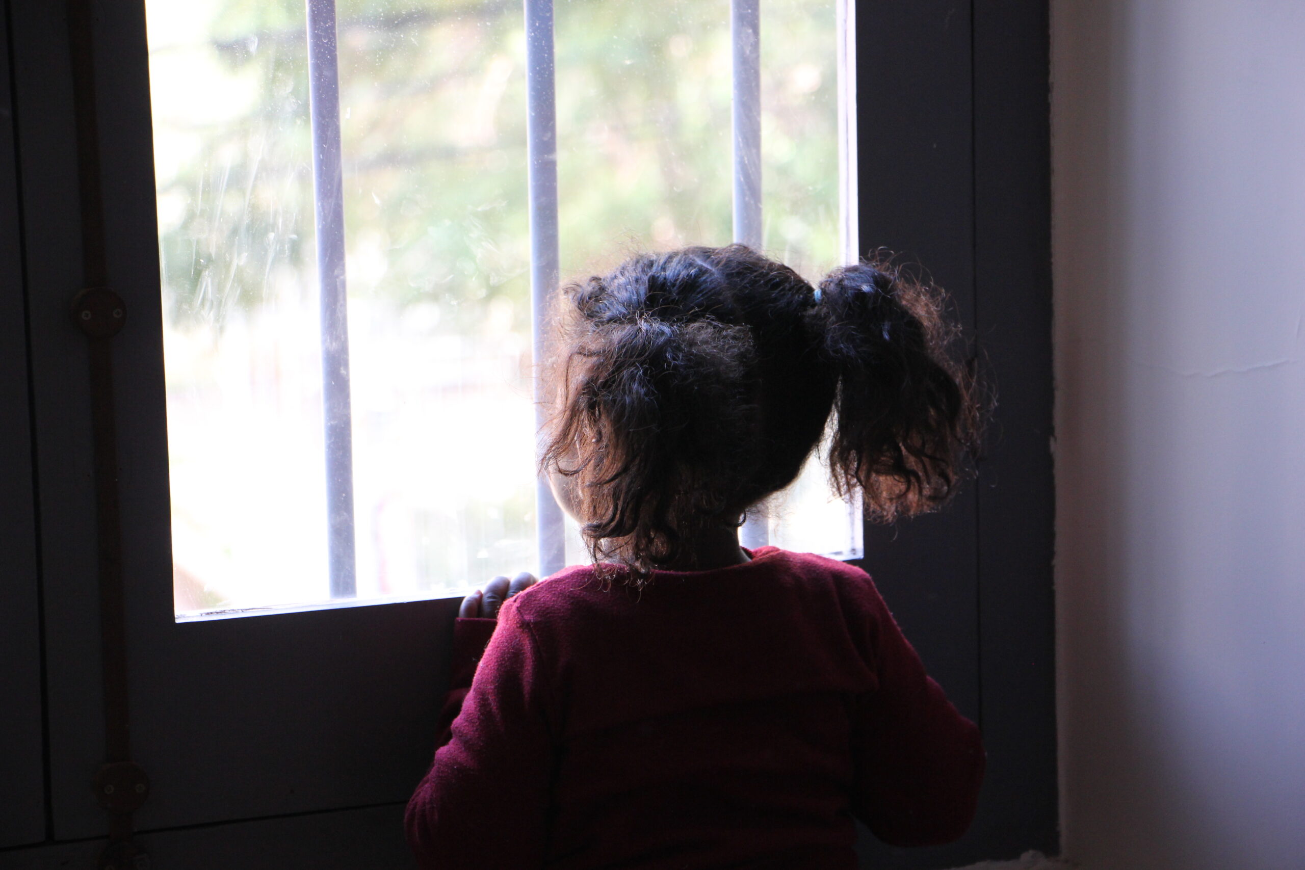 a girl looks out from a window in Lebanon.