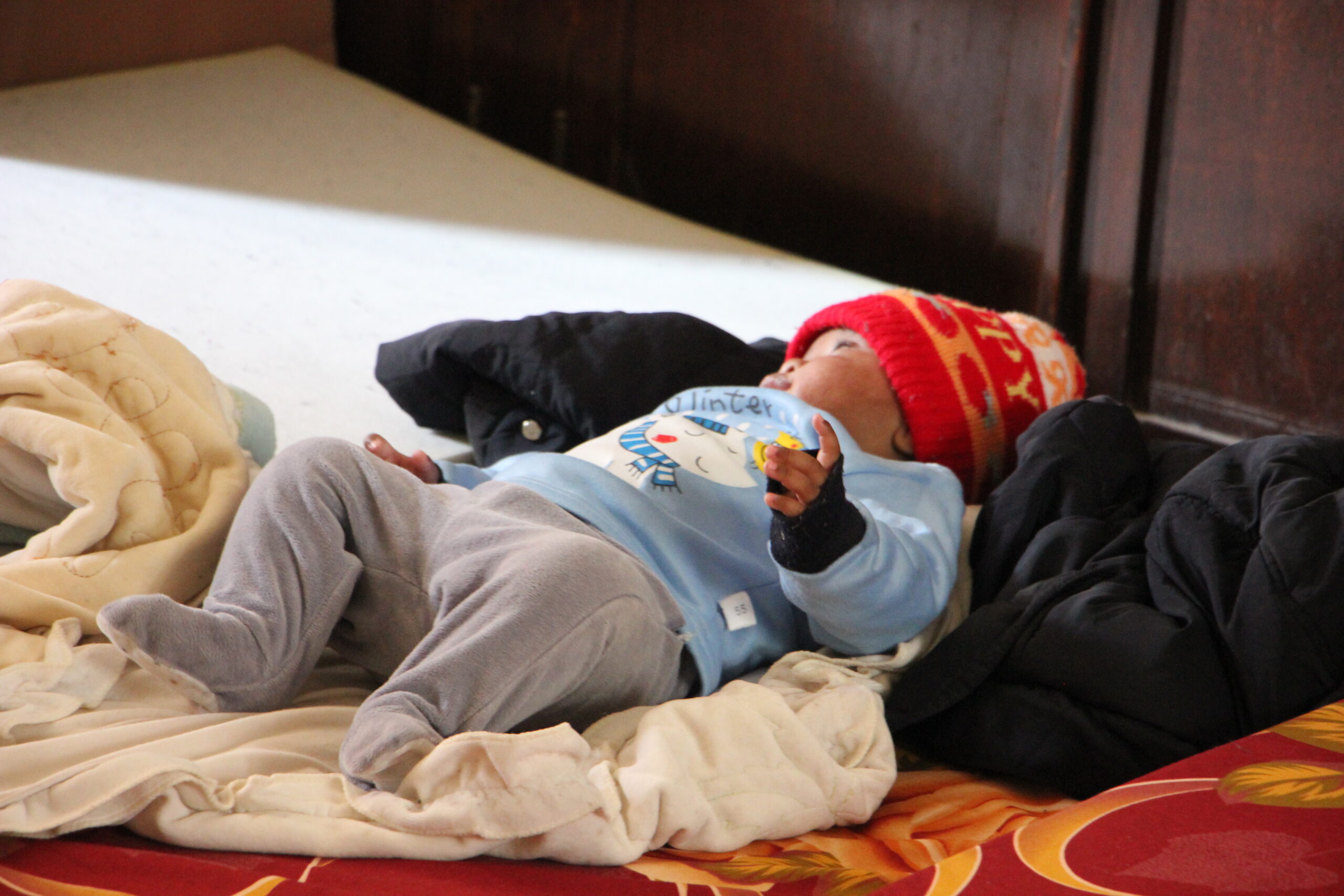 A baby sleeps on a mattress on the floor as families take shelter in St Joseph's Church in Beirut
