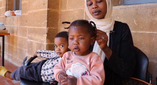 Zahraa is sat on a chair with her children. her daughter sits on her lap.