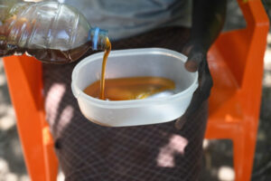 Mary pours out some of her harvested honey into a bowl. the image is a lose up of her hands. 