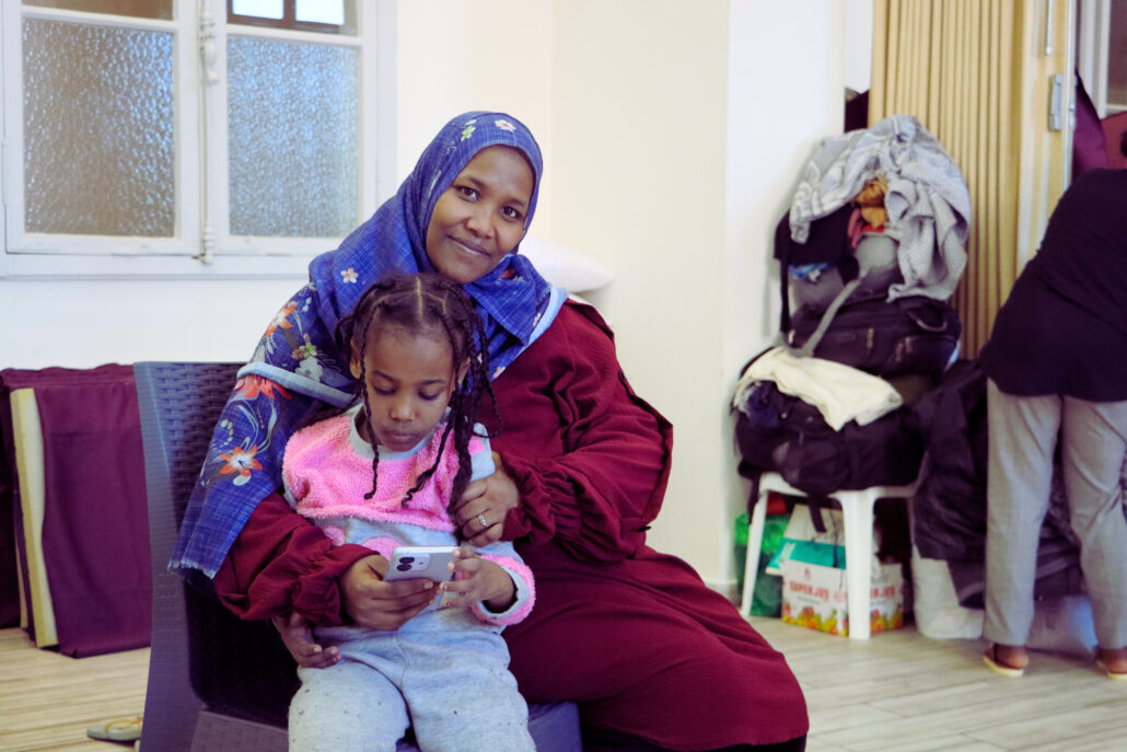 Rudayna, a Sudanese refugee, sits with her daughter on her lap.